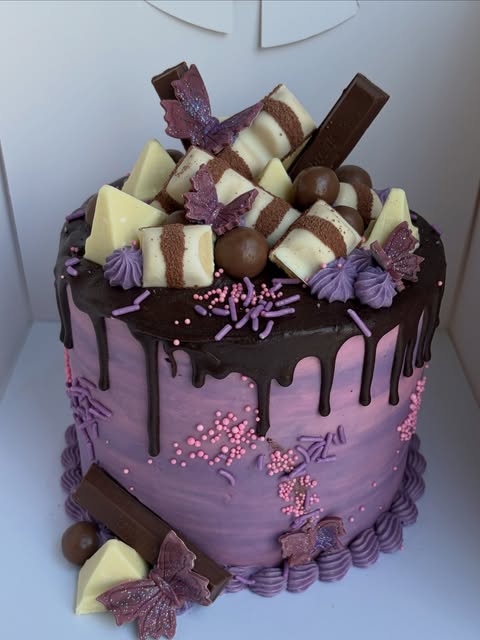 Lovelybakes purple cake with chocolate drip, chocolates and butterfly decorations